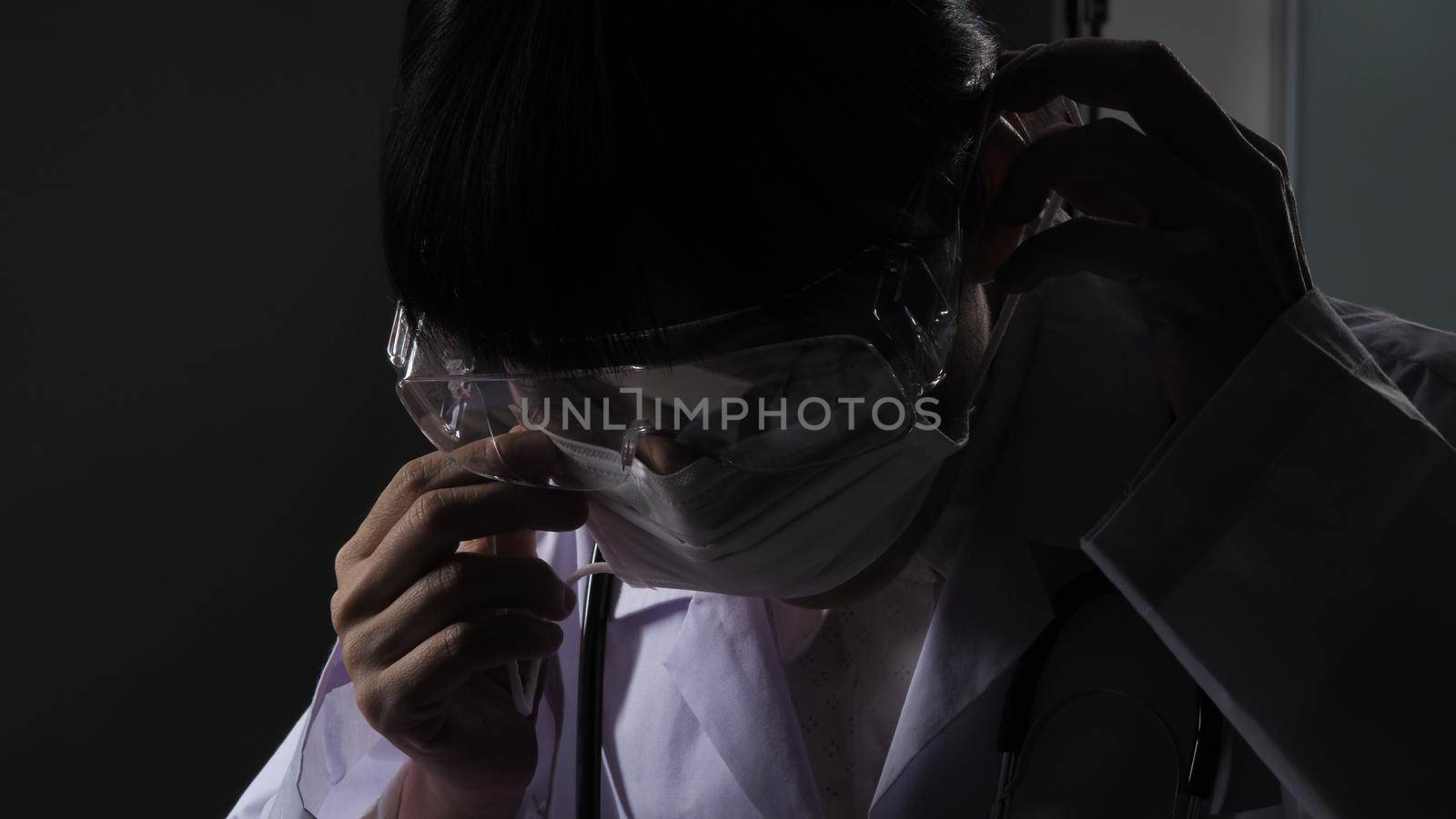 Doctor wearing protection face mask against coronavirus before work night ward by gnepphoto