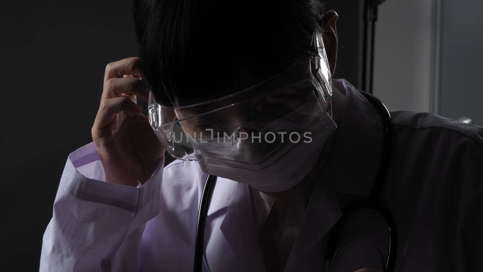 Doctor wearing protection face mask against coronavirus before work night ward by gnepphoto