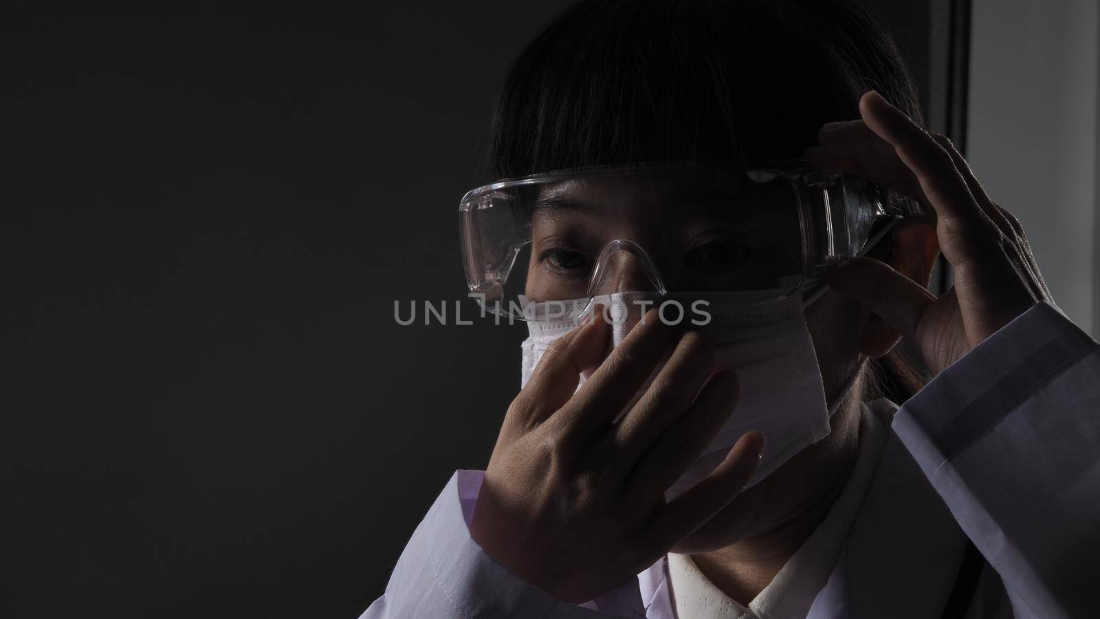 Doctor wearing protection face mask against coronavirus before work night ward by gnepphoto