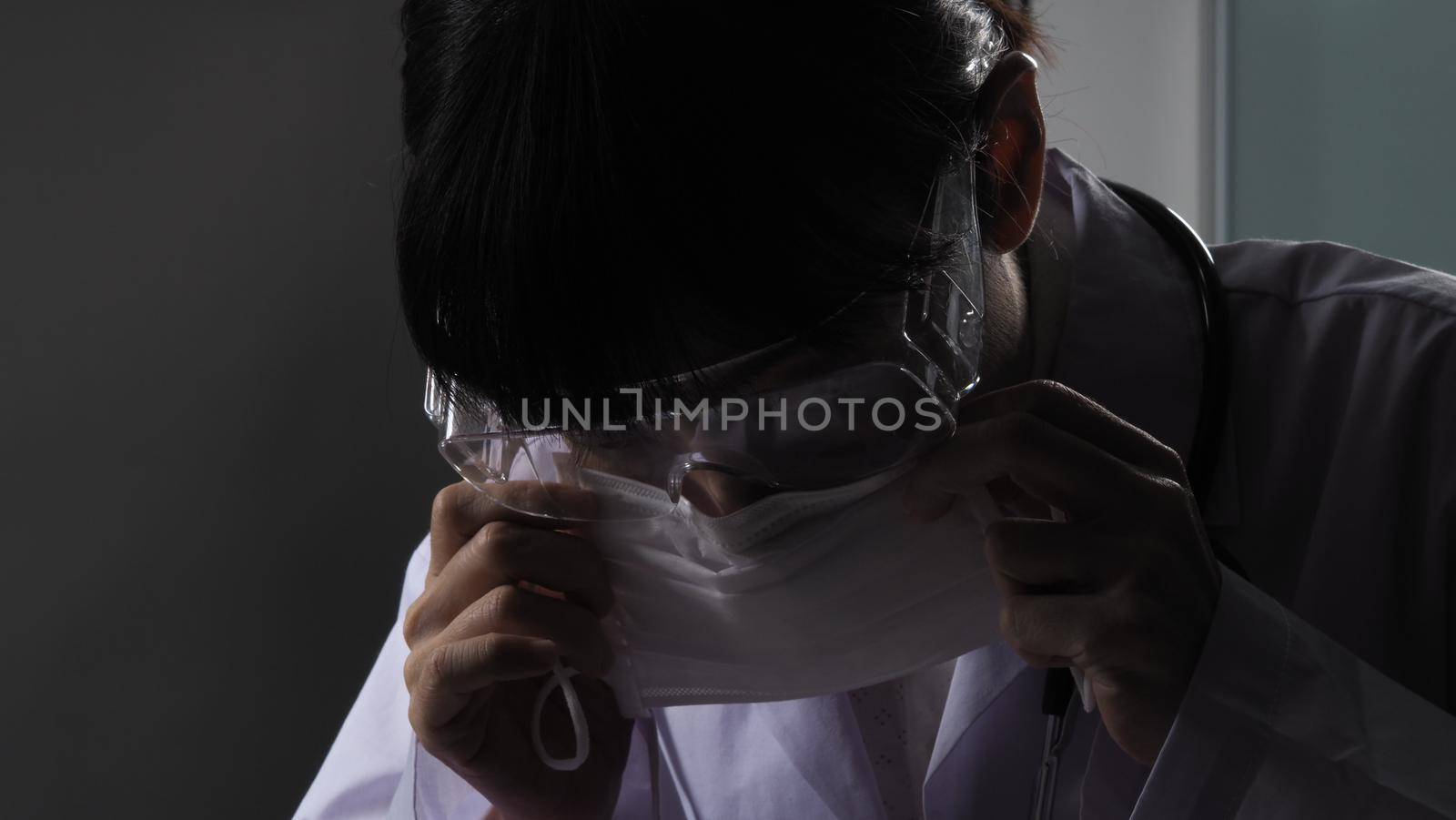 Doctor wearing protection face mask against coronavirus before work night ward by gnepphoto