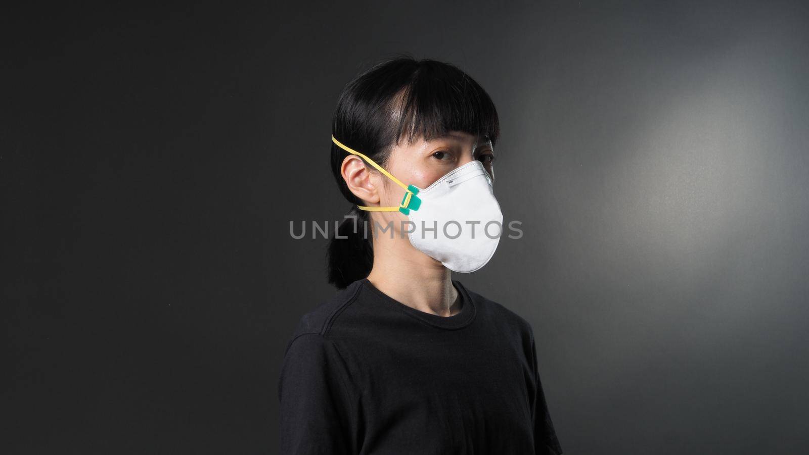 Asian girl in a mask on a black background in Coronavirus Quarantine situation.  by gnepphoto