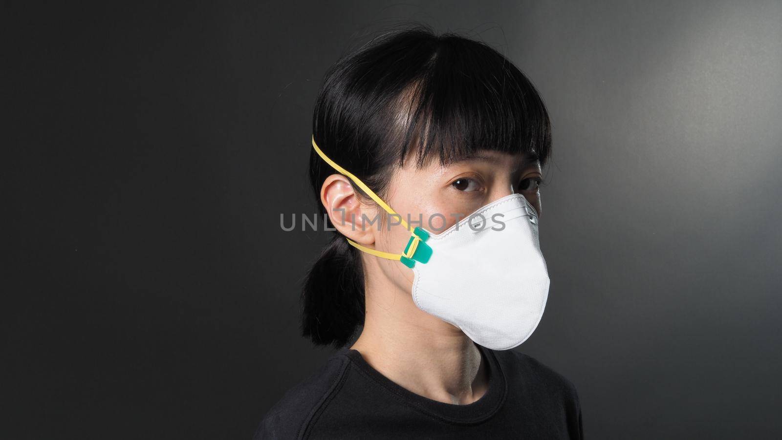 Asian girl in a mask on a black background in Coronavirus Quarantine situation.  by gnepphoto