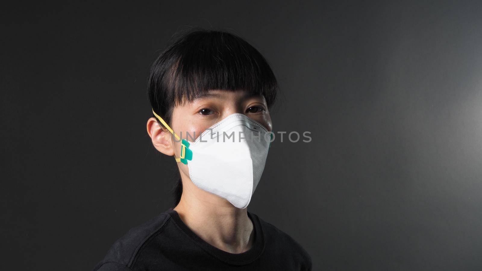 Asian girl in a mask on a black background in Coronavirus Quarantine situation. Title about the outbreak of the corona virus in the World, illness. Epidemic. female wearing N95 mask studio black background