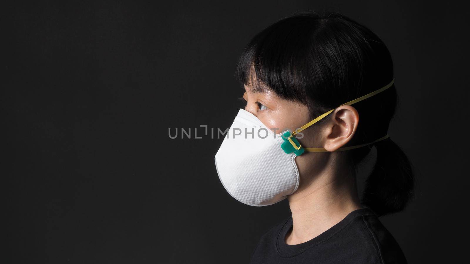 Asian girl in a mask on a black background in Coronavirus Quarantine situation. Title about the outbreak of the corona virus in the World, illness. Epidemic. female wearing N95 mask studio black background