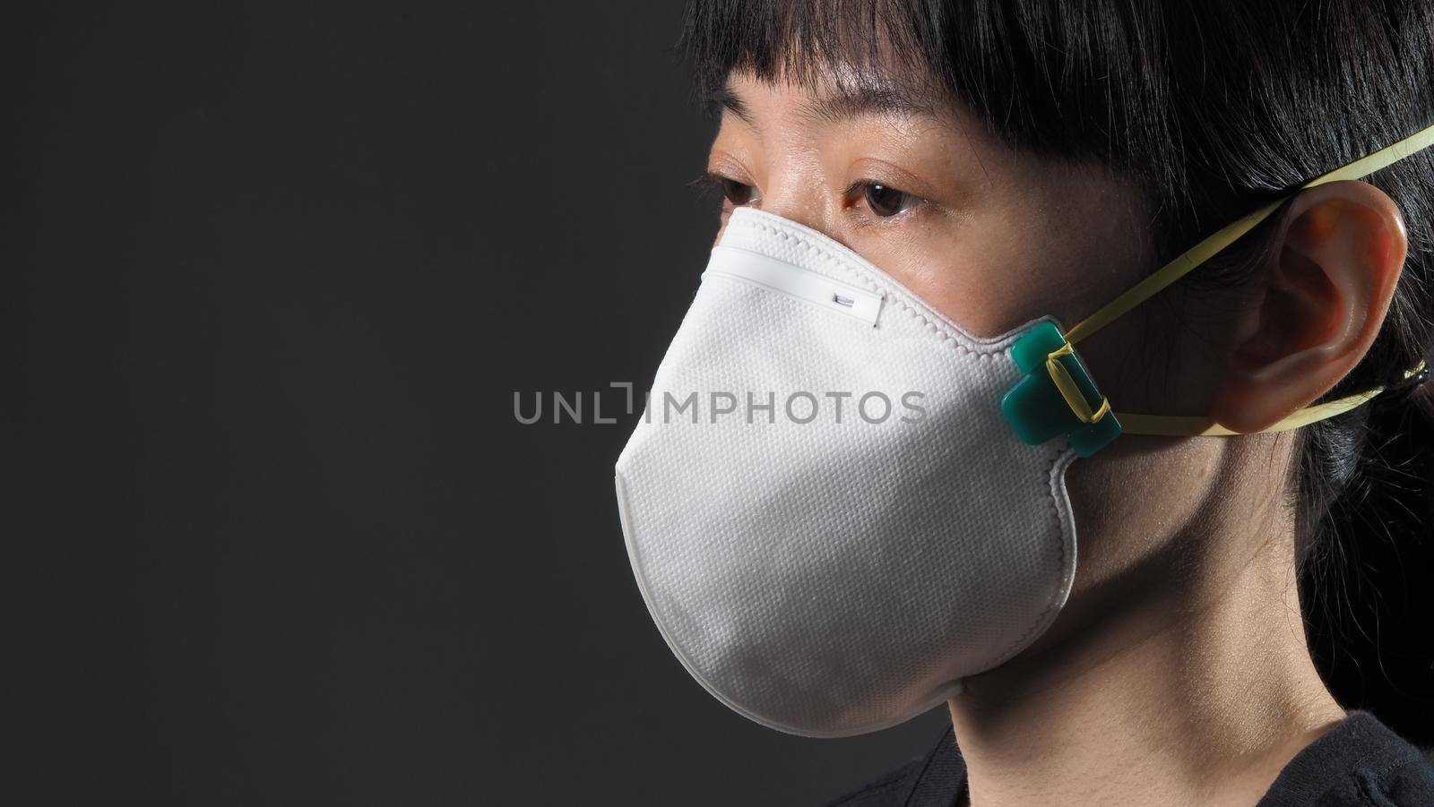 Asian girl in a mask on a black background in Coronavirus Quarantine situation. Title about the outbreak of the corona virus in the World, illness. Epidemic. female wearing N95 mask studio black background