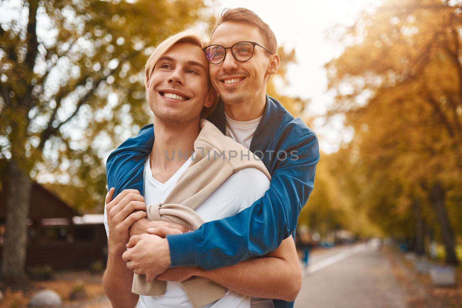 Loving gay couple walking outdoors. Two handsome men having romantic date in park. LGBT concept.