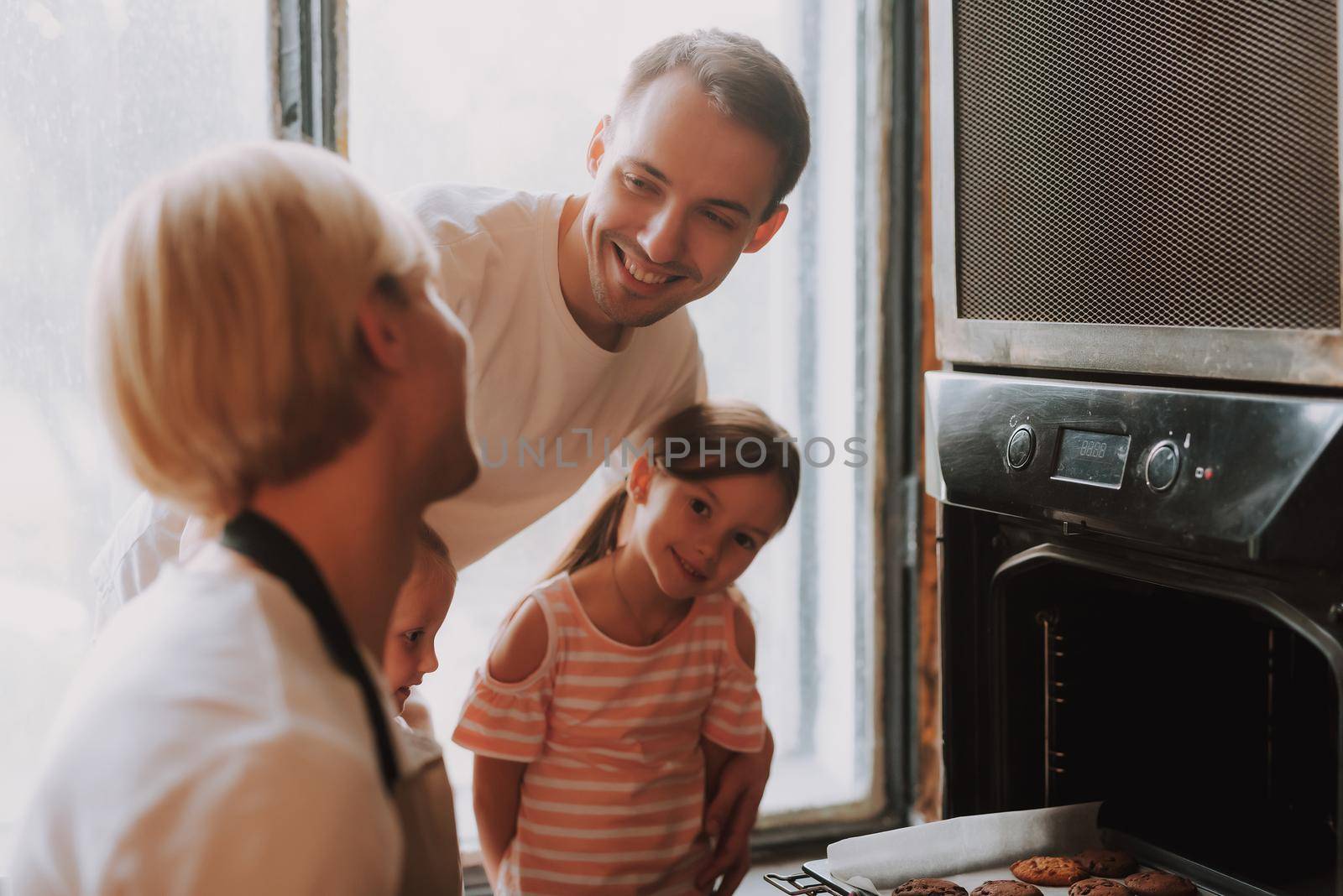 Gay couple with their adopted cute daughters cooking on kitchen. Lgbt family at home. Happy family making cookies together.