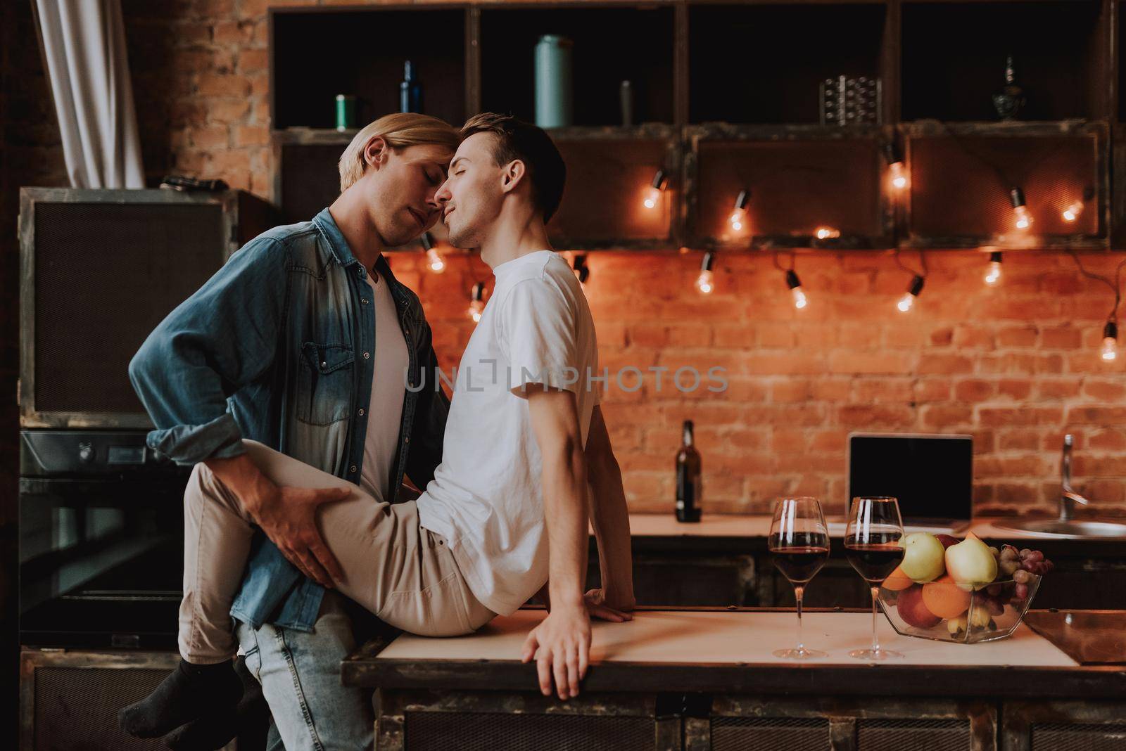 Loving gay couple at home. Two handsome passionate men hugging and kissing on kitchen. LGBT concept.
