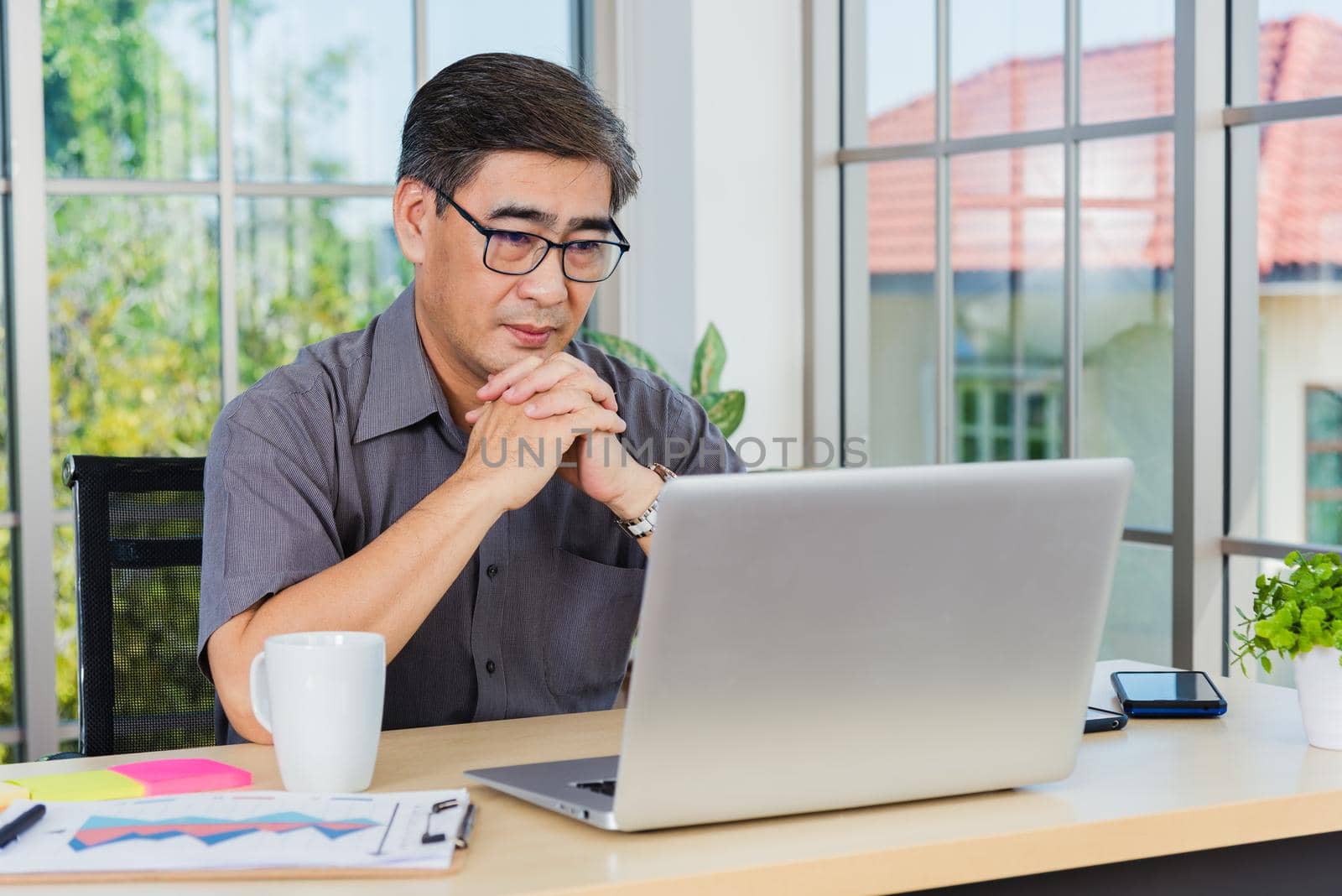 Asian senior business man working online on a modern laptop computer by Sorapop