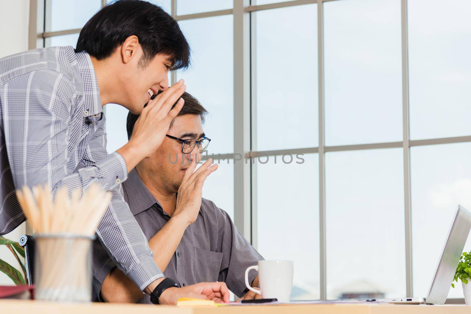 Asian senior and young business man working online on a modern laptop computer he looking the screen meeting online. Old and junior businessman using video call conference on desk table at office