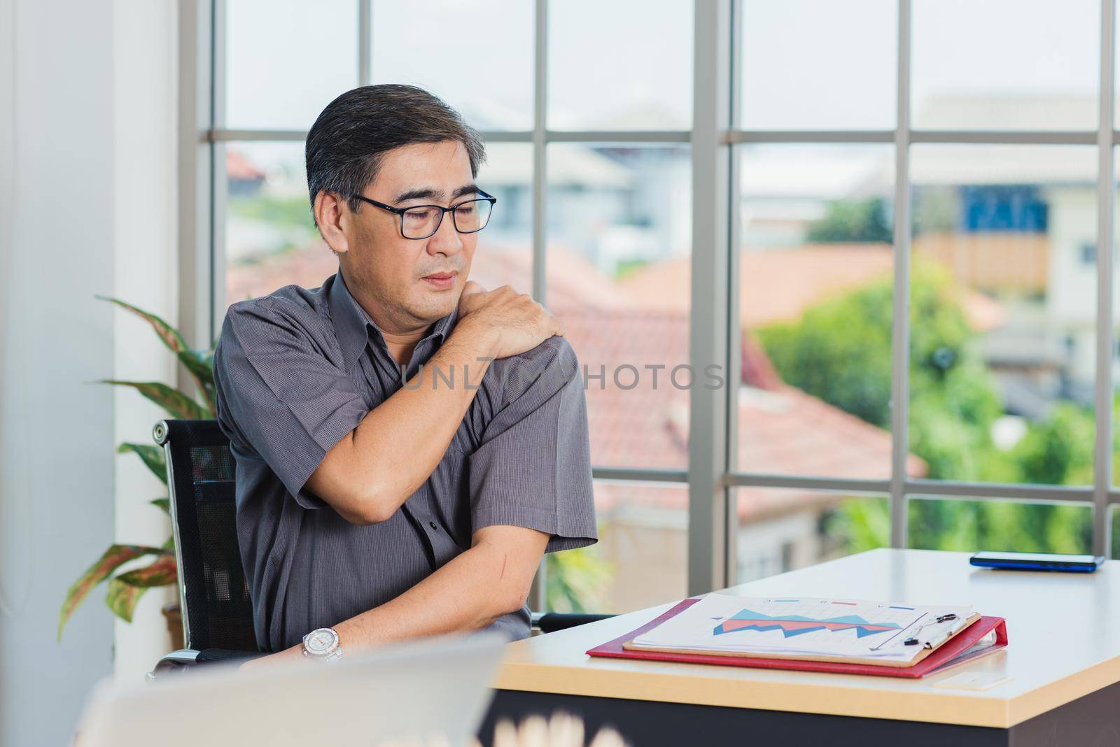 Asian hard senior businessman working with laptop computer has a problem with shoulder pain. Old man feeling pain after sitting at desk long time, Healthcare and medicine office syndrome concept
