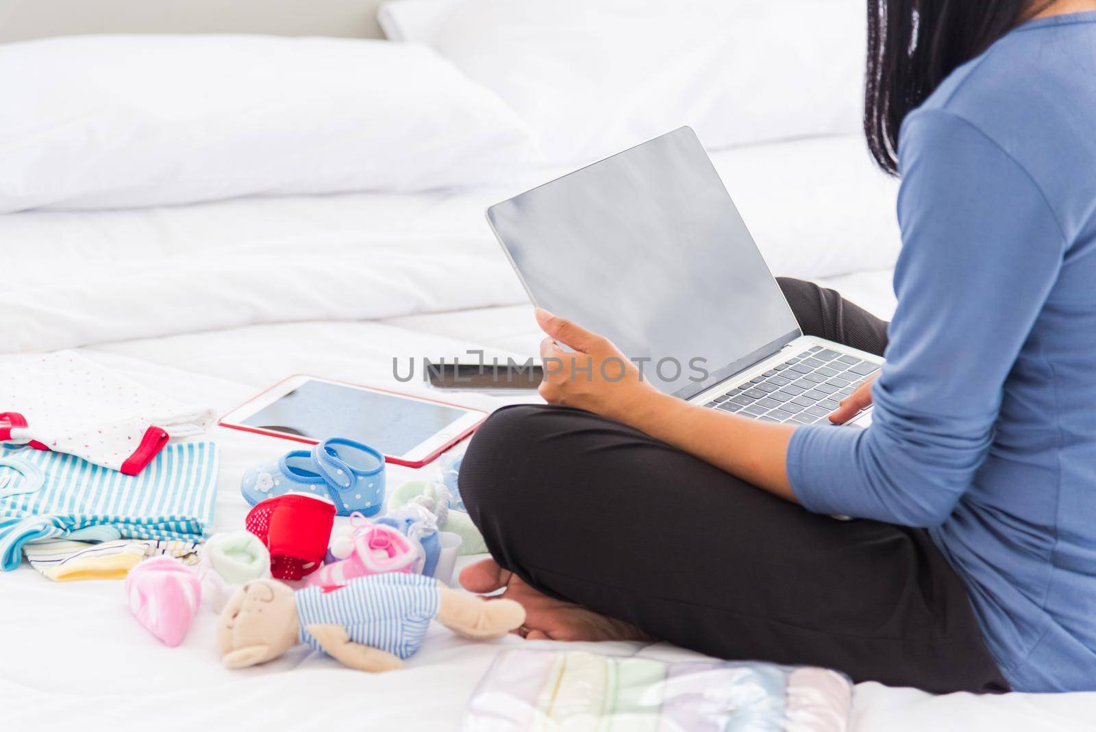 mother shopping online for her baby clothes on laptop computer by Sorapop