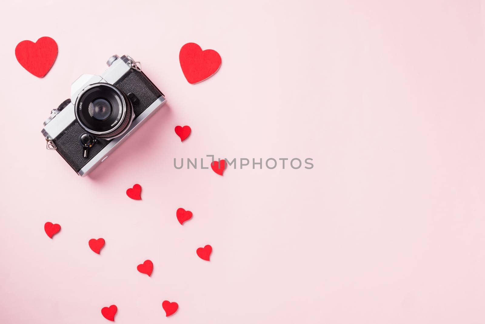 Valentines' day background. Vintage retro camera and red hearts composition greeting card love Valentines day I love photography concept on pink background with copy space. Top View from above