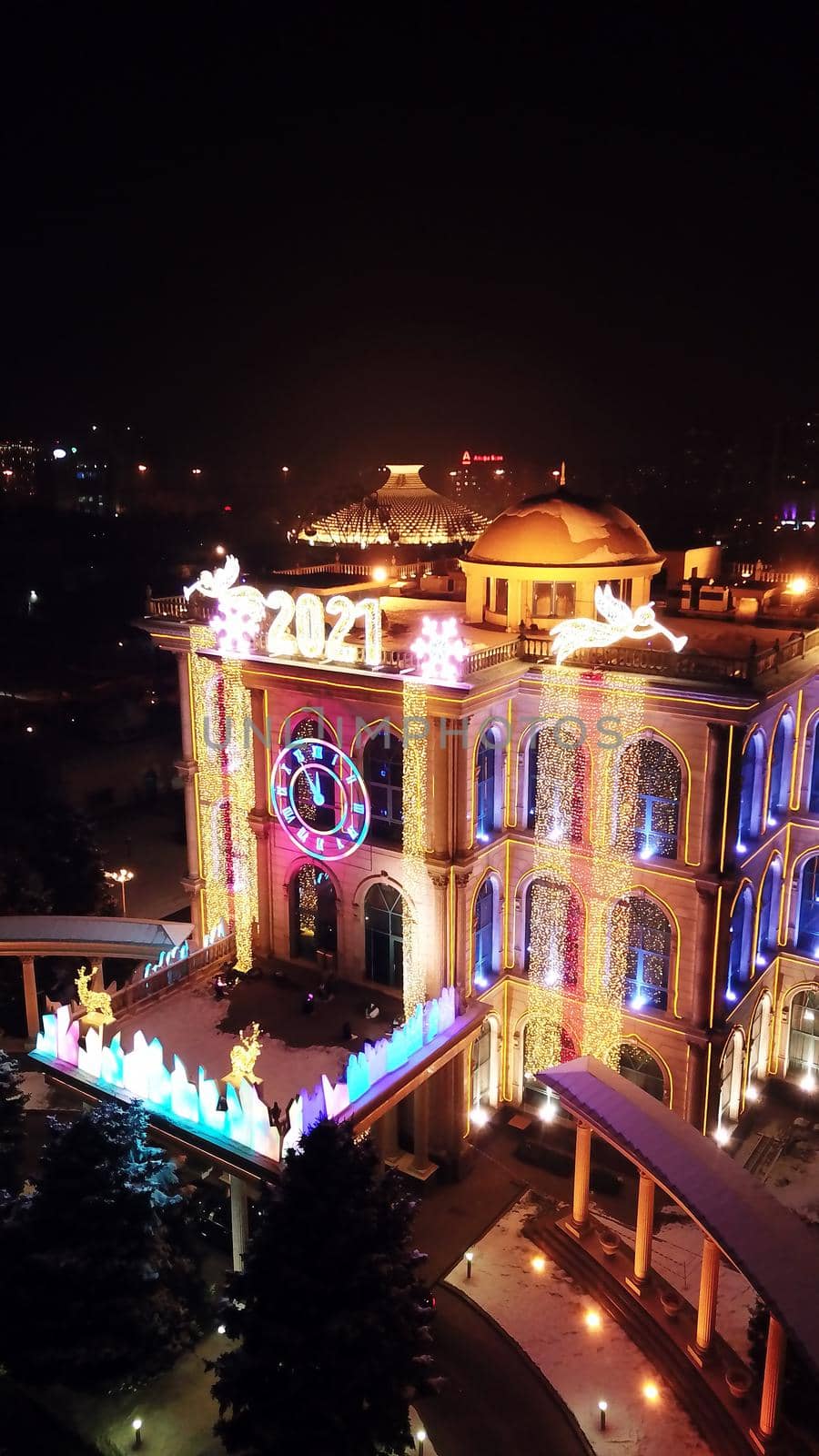 The city is decorated for Christmas and new year. Buildings, garlands, Christmas trees, fences and the square glow with different lights. People relax, enjoy the winter and holiday. View from a drone