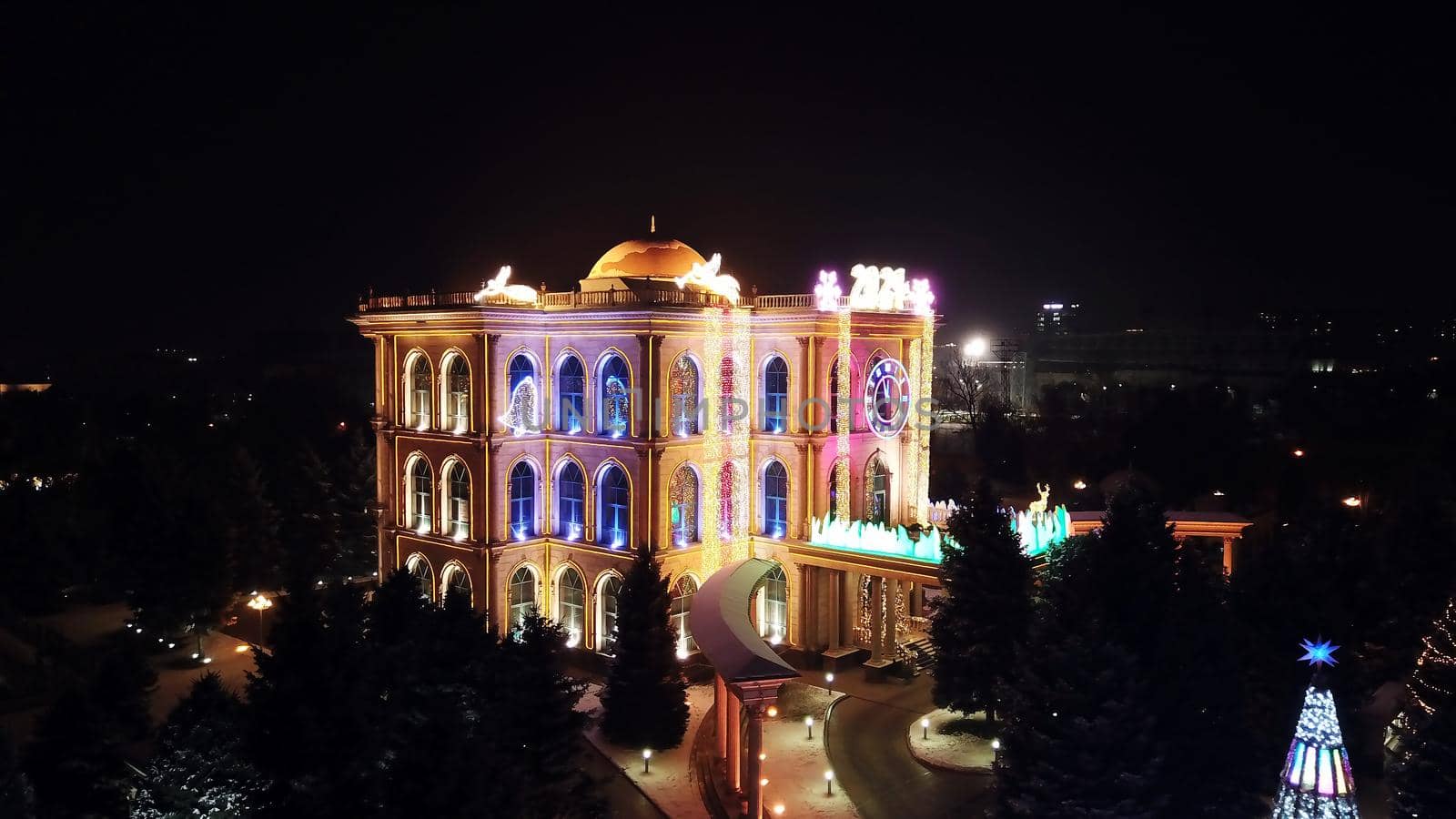 The city is decorated for Christmas and new year. Buildings, garlands, Christmas trees, fences and the square glow with different lights. People relax, enjoy the winter and holiday. View from a drone