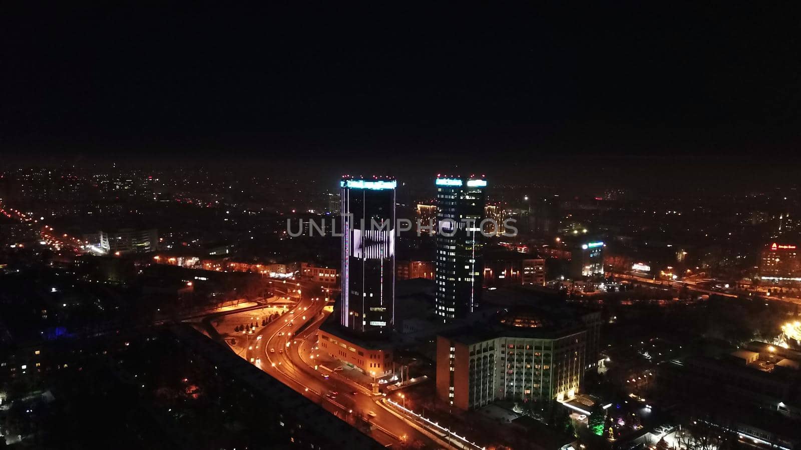 The city is decorated for Christmas and new year. Buildings, garlands, Christmas trees, fences and the square glow with different lights. People relax, enjoy the winter and holiday. View from a drone