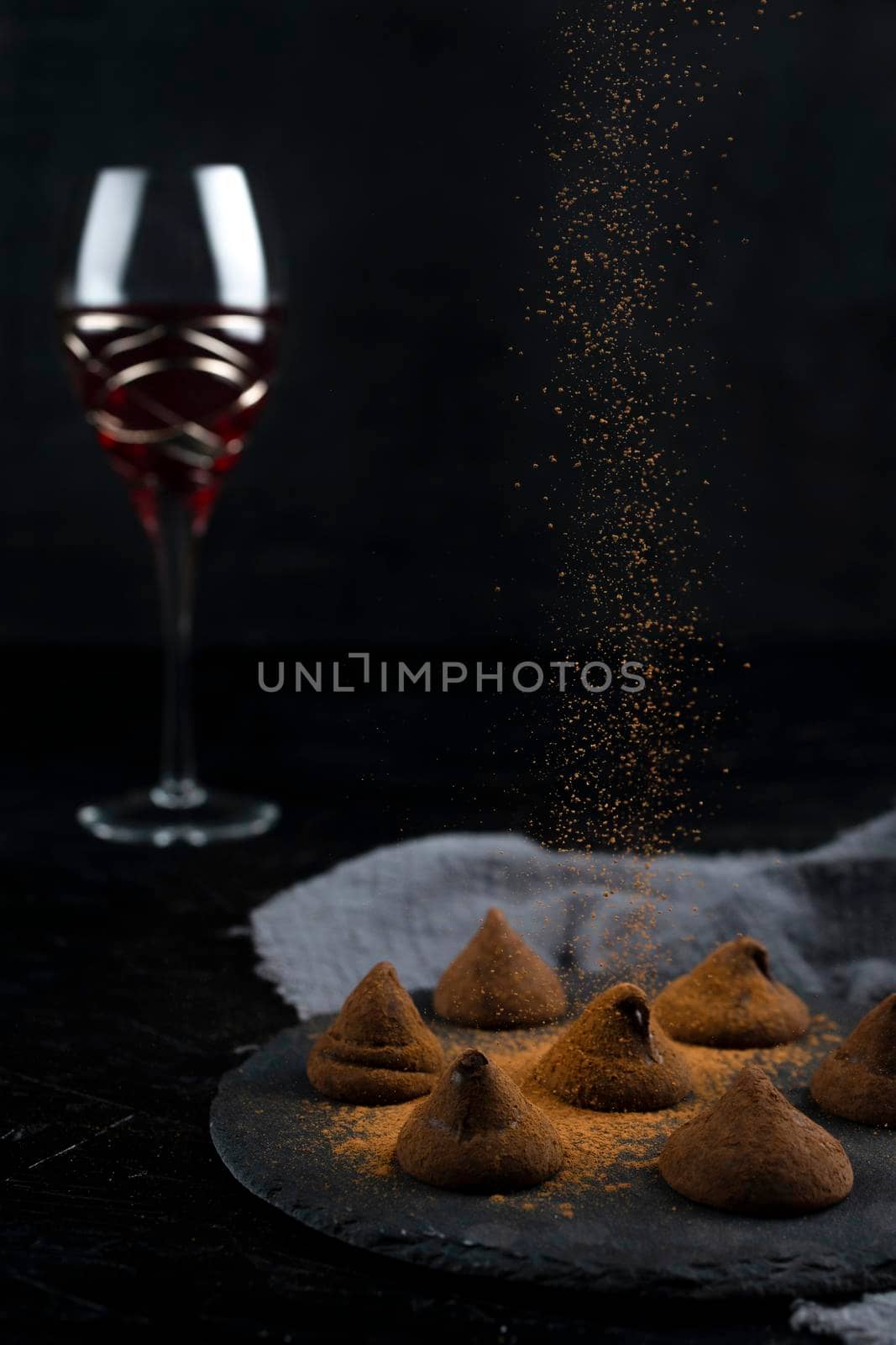 Delicious chocolate truffles and red wine on black background.