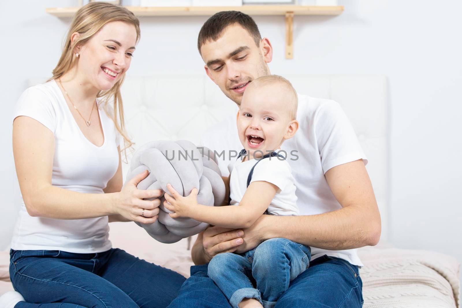 Mom, dad and little son are playing at home. Young family with a child.