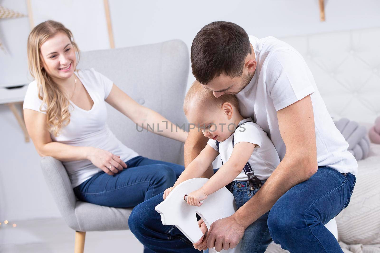 Mom, dad and little son are playing at home. Young family with a child.