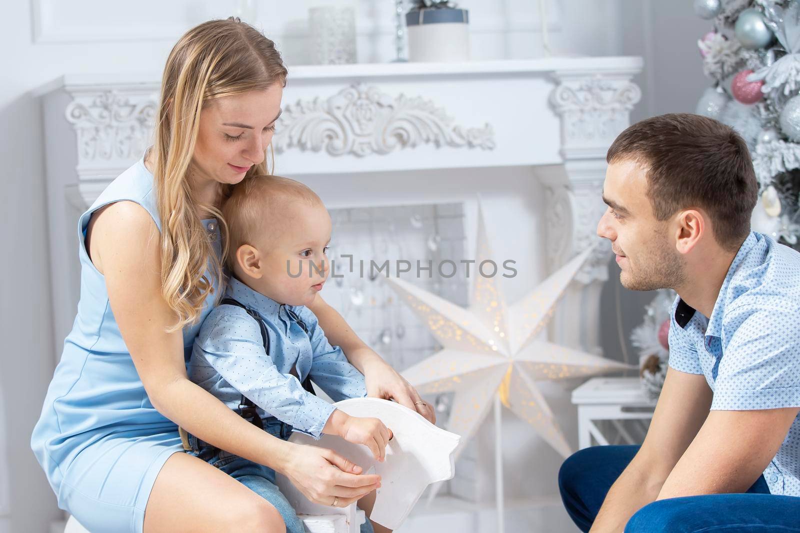 Family at Christmas. Mother father and child play against the background of a Christmas tree. Parents and son in the new year.