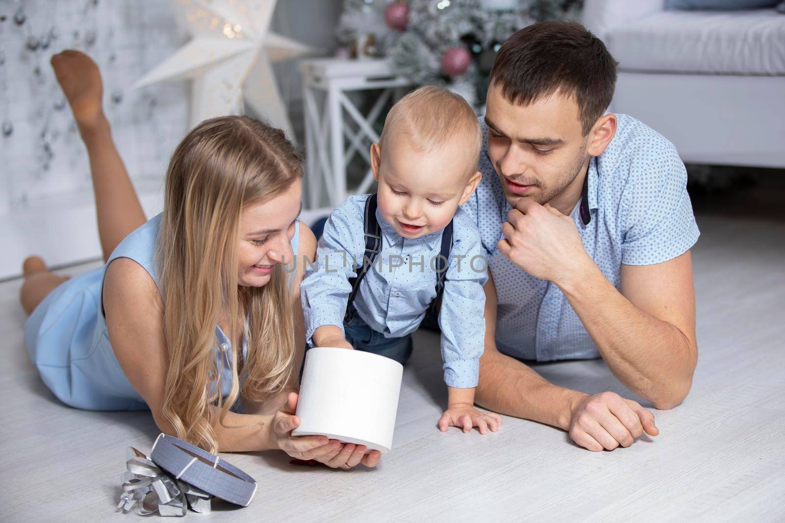 Family at Christmas with gifts. Mother father and baby at the Christmas tree. New year holidays