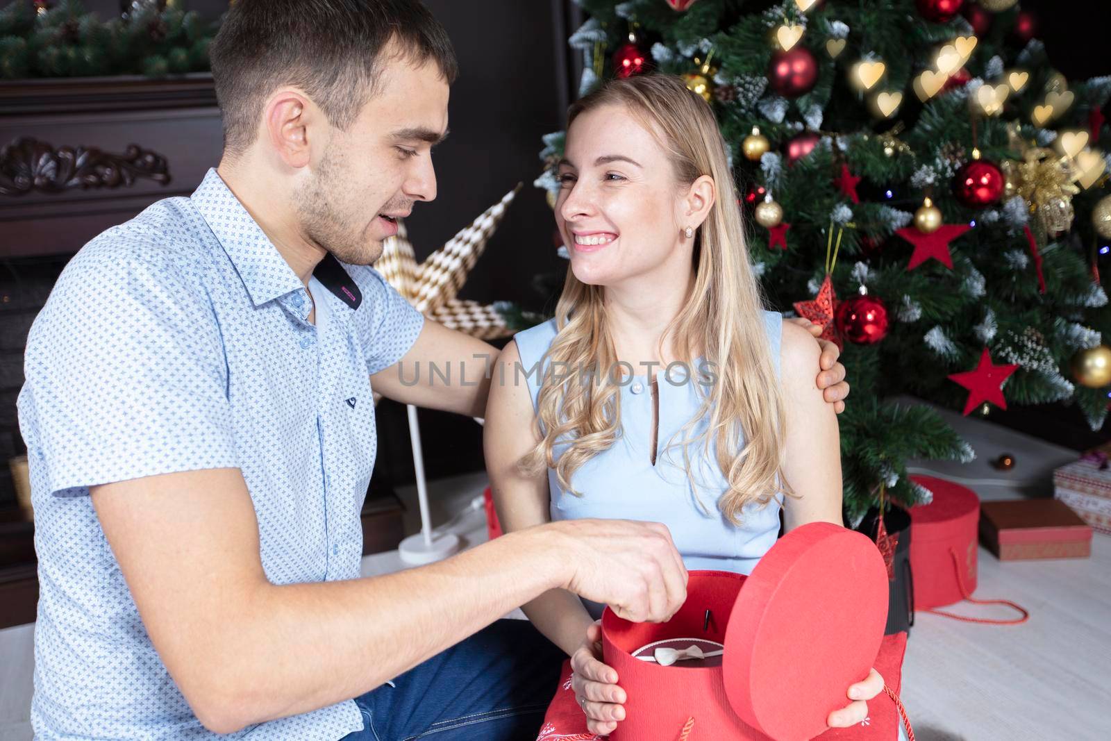 Family at Christmas. The husband gives his wife a Christmas present. Lovers on the background of the Christmas tree.