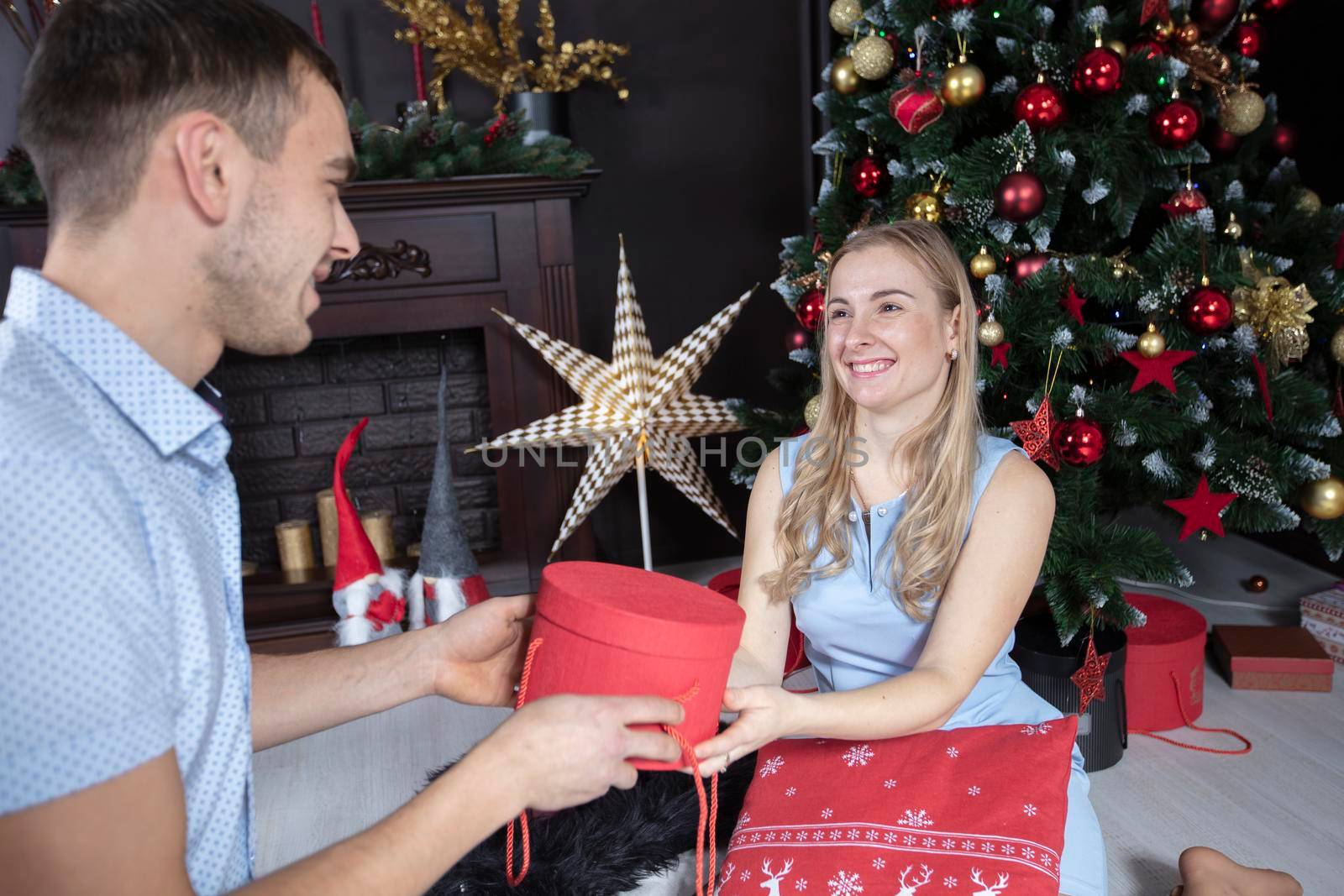 Family at Christmas. The husband gives his wife a Christmas present. Lovers on the background of the Christmas tree.