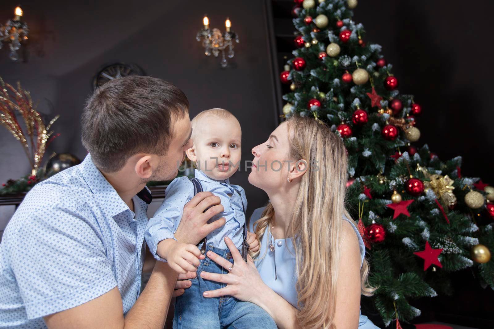 Family at Christmas. Mother father and child play against the background of a Christmas tree. Parents and son in the new year.