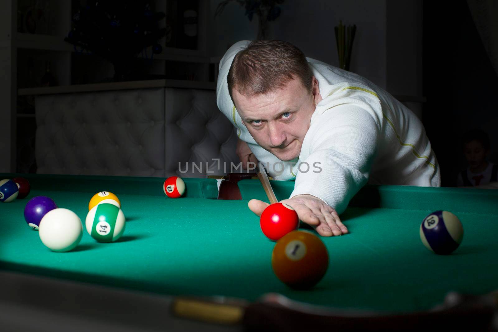 A man plays billiards. A man with a cue in his hands.