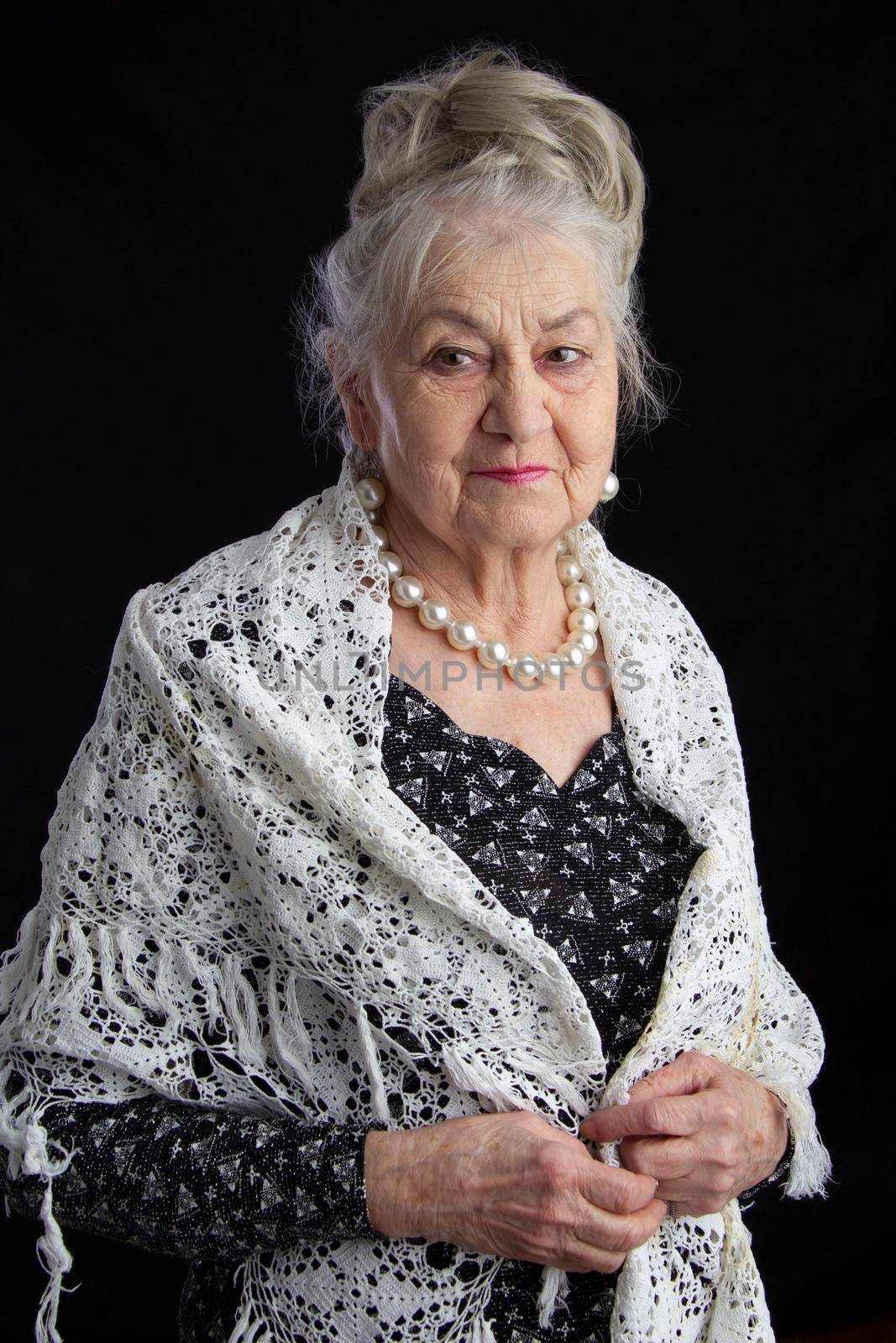 Portrait of a ninety year old woman. Beautiful old lady. Luxurious grandmother on a black background. Elderly beauty. The gray-haired well-groomed pensioner.