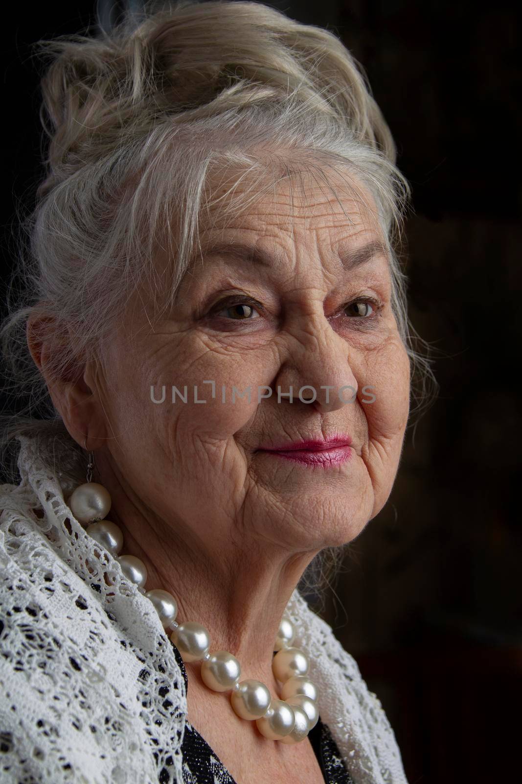 Portrait of a ninety year old woman. Beautiful old lady. Luxurious grandmother on a black background. Elderly beauty. The gray-haired well-groomed pensioner.