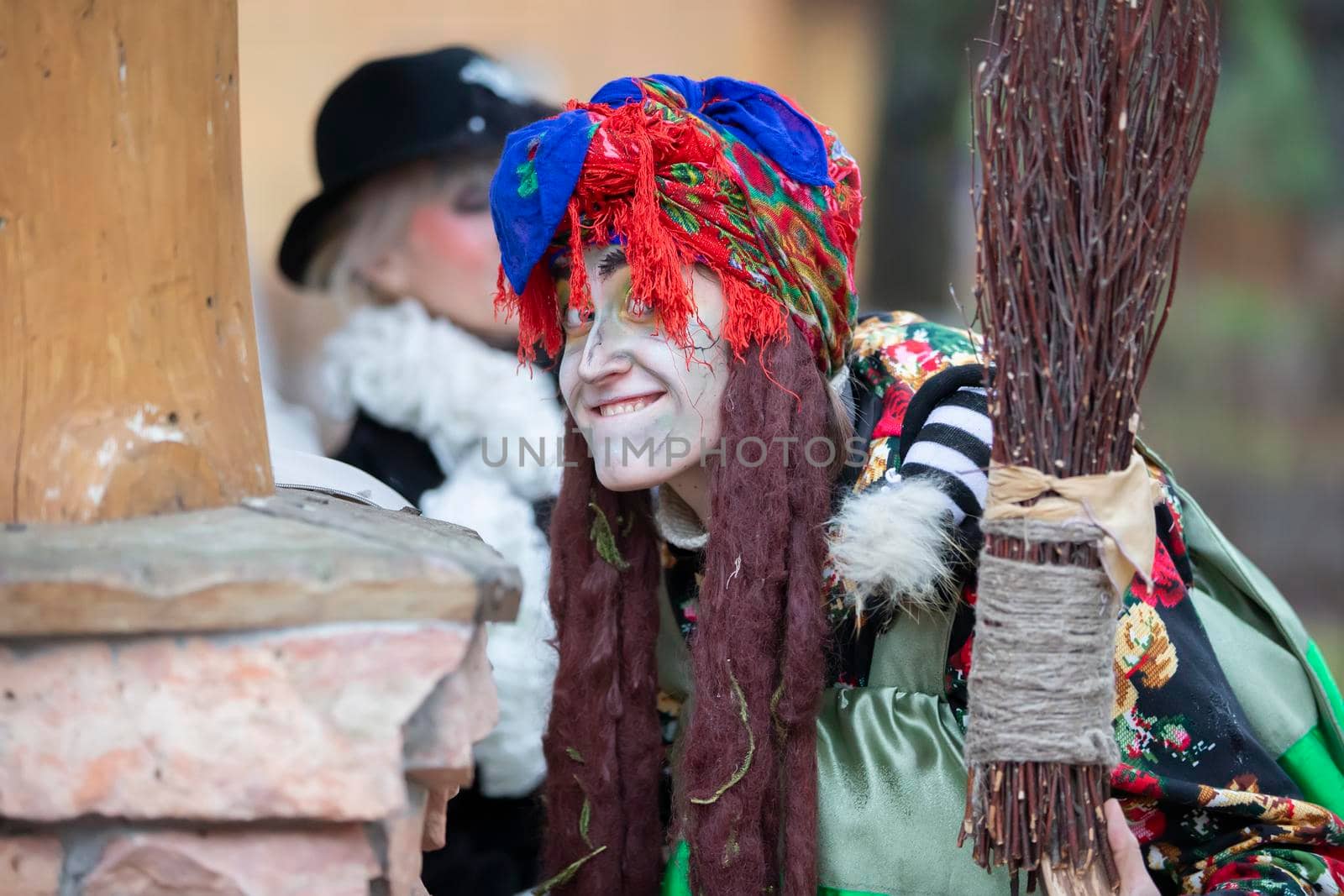 Baba Yaga with a broom near a wooden hut.