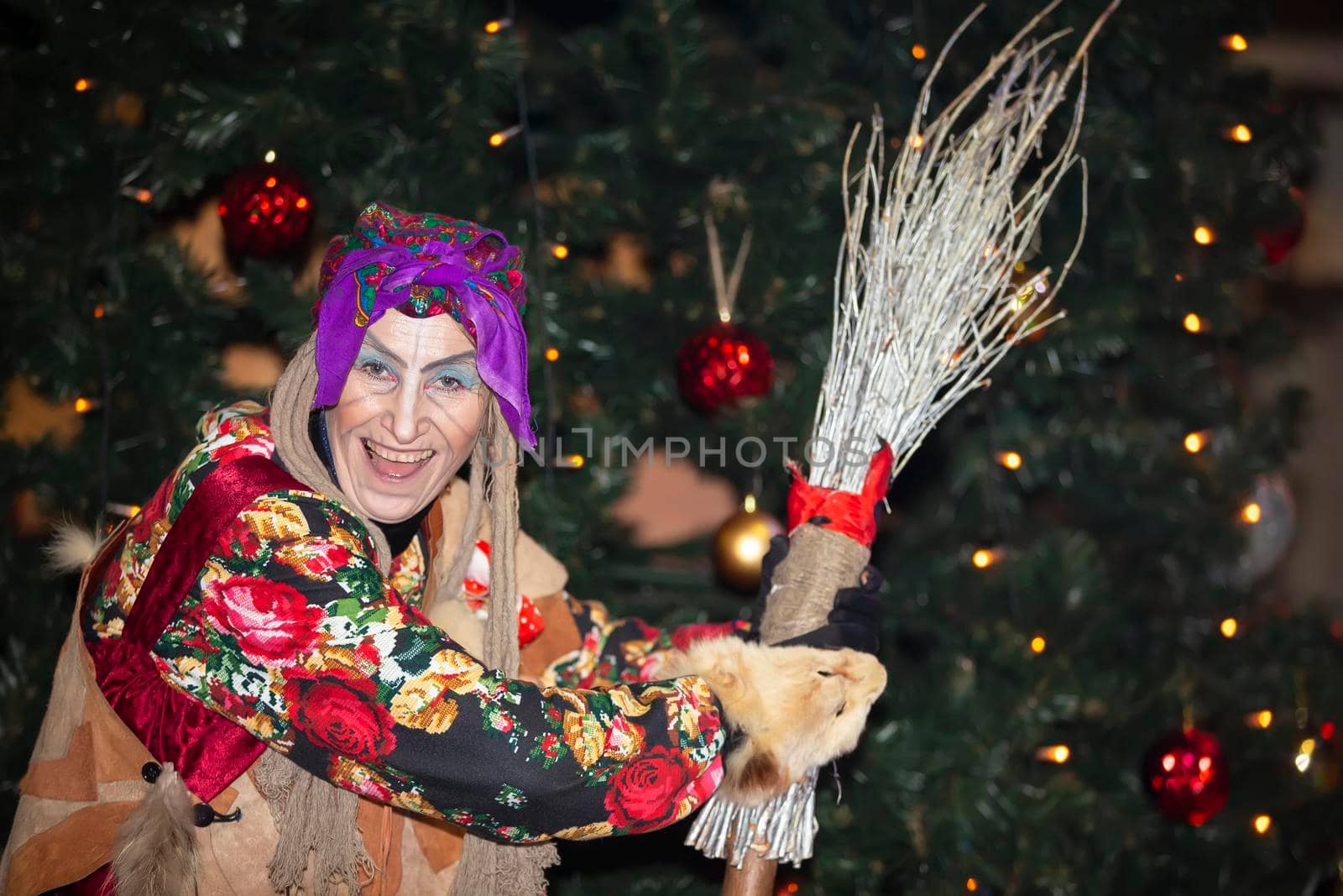 Baba Yaga with a broom on the background of the Christmas tree.