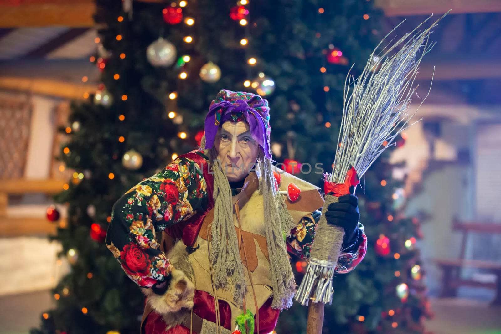 Baba Yaga with a broom on the background of the Christmas tree.