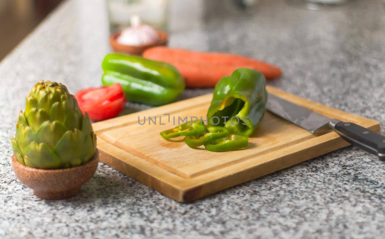 Bell pepper on a cutting board, and fresh ingredients over a kitchen countertop. by hernan_hyper