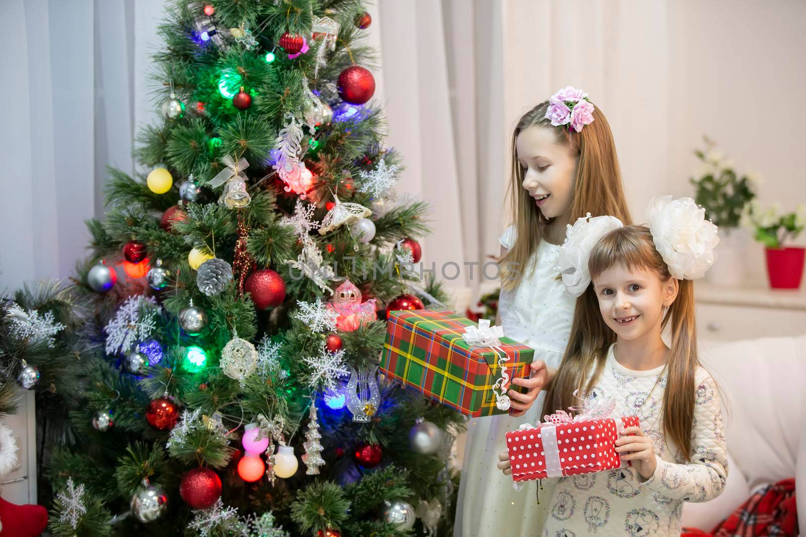 Joyful children at the Christmas tree with gifts on Christmas holidays.
