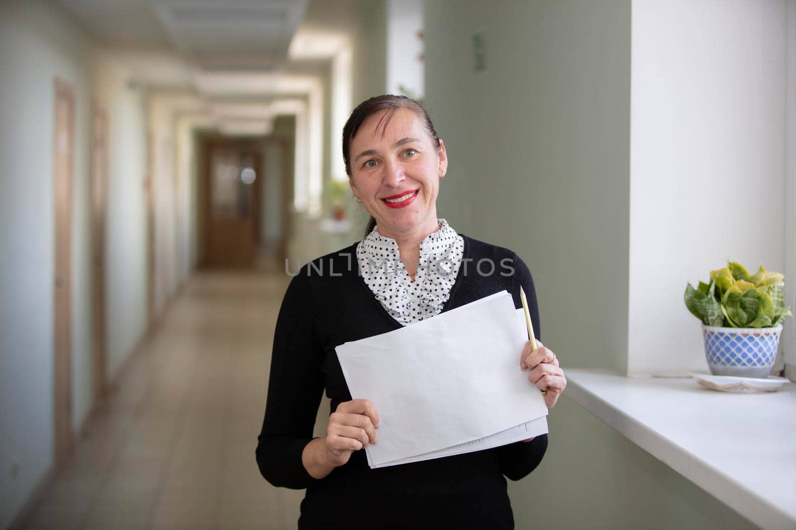 Happy woman at work. Female employee in the hallway with a piece of paper.