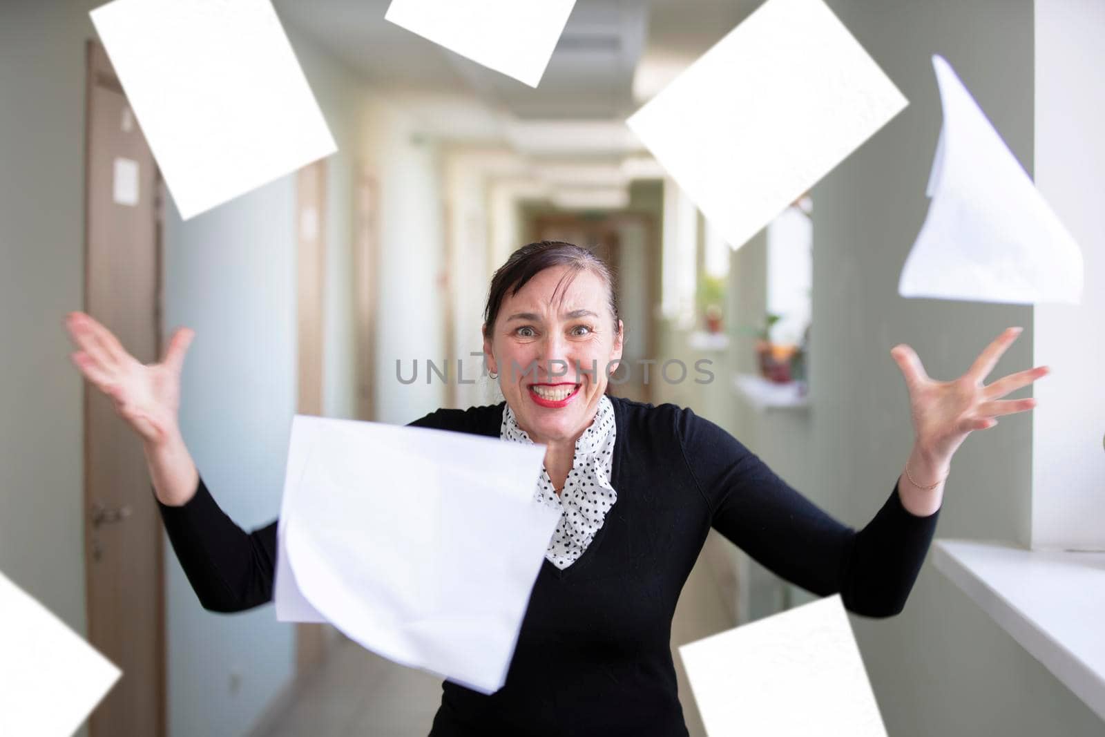A woman in the office scatters papers. Nervous employee.