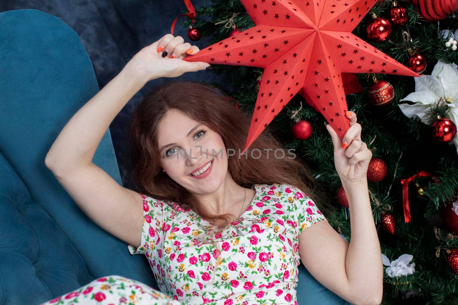 Portrait of a beautiful woman on the background of the Christmas tree. Girl with a red star.