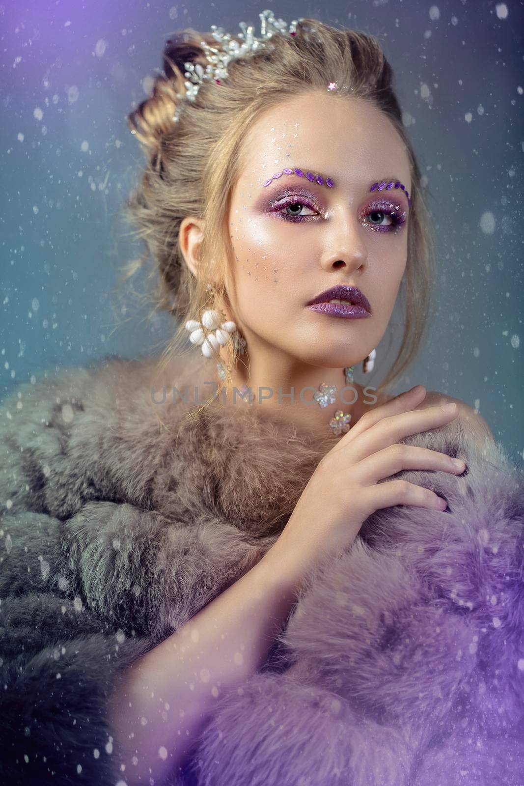 Winter girl in a fur coat in purple background. Luxurious model with beautiful makeup. Young fashionable woman.