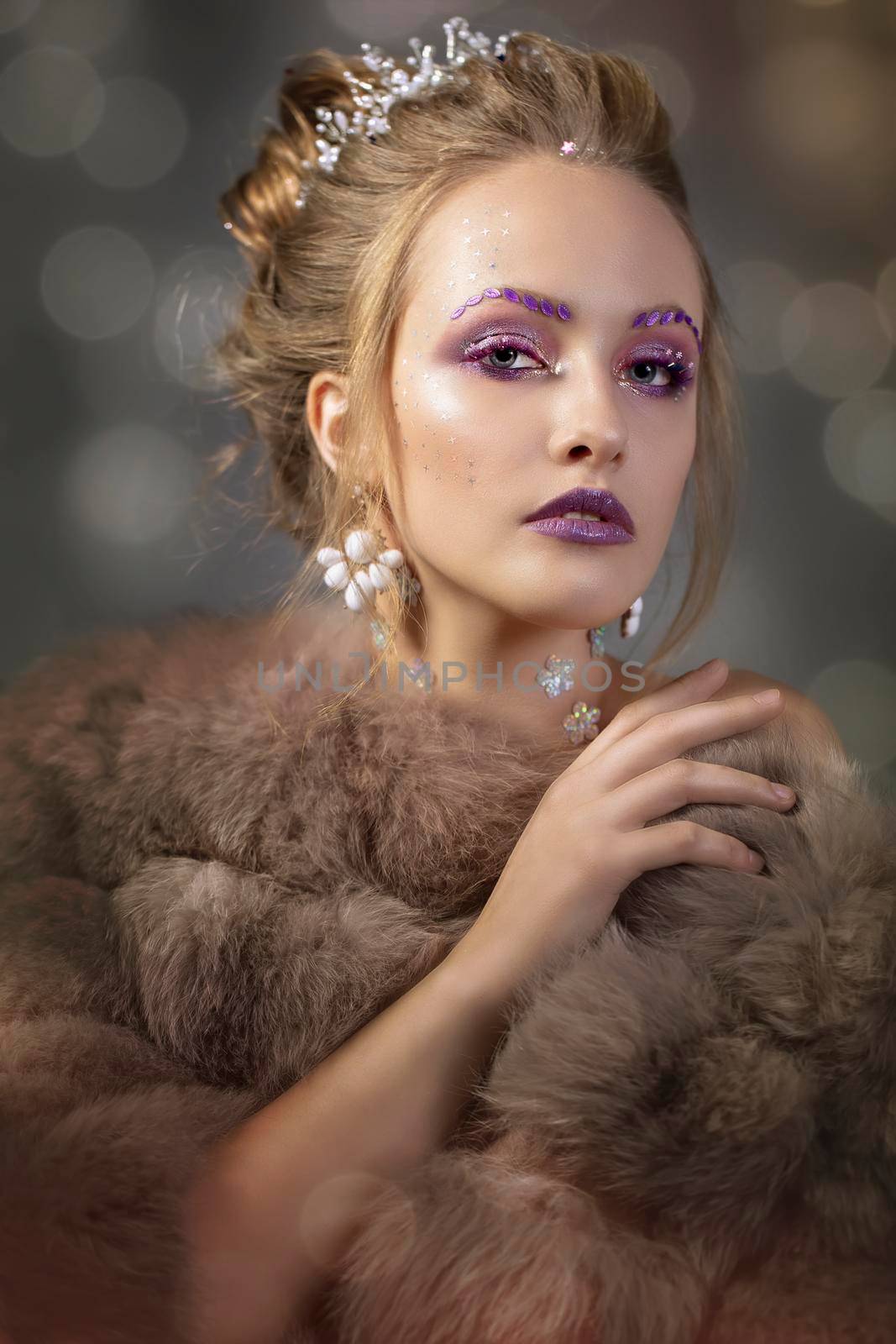 Luxurious girl with a beautiful make-up in a fur coat. Beauty in furs. Model on a bokeh background. Young beautiful woman.Violet makeup.