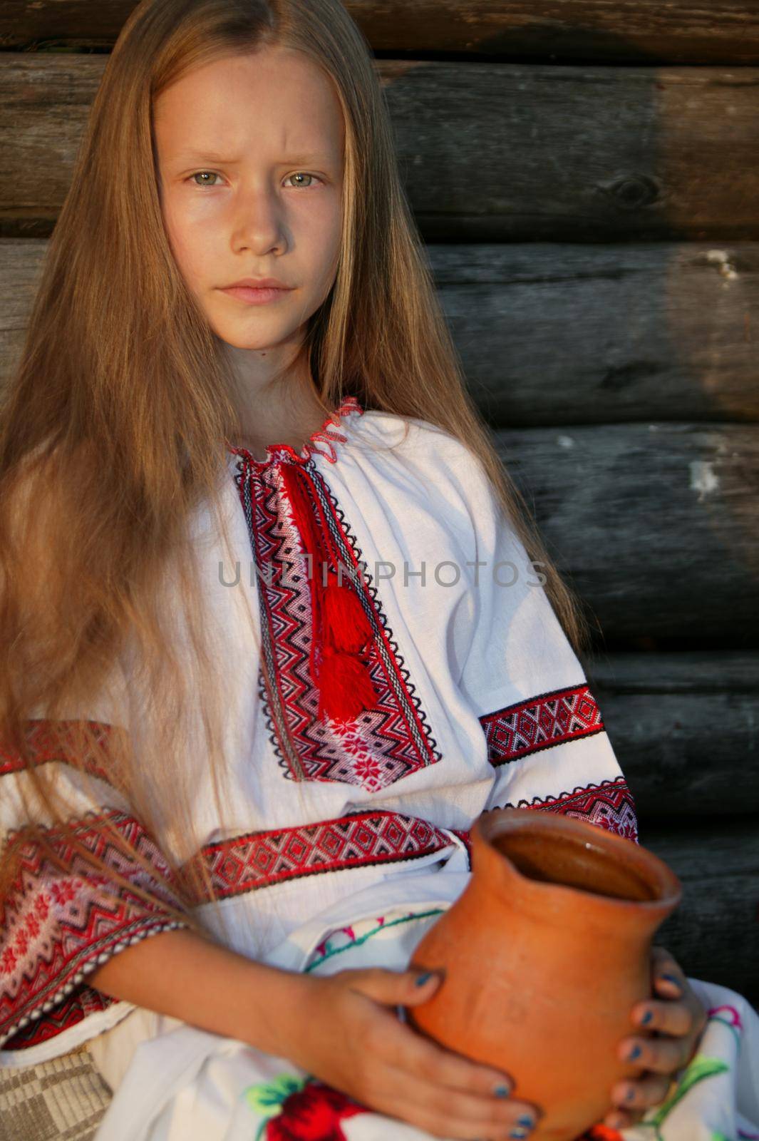 Slavic girl in an embroidered shirt with a clay jug. Ukrainian girl. The blonde in national dress.