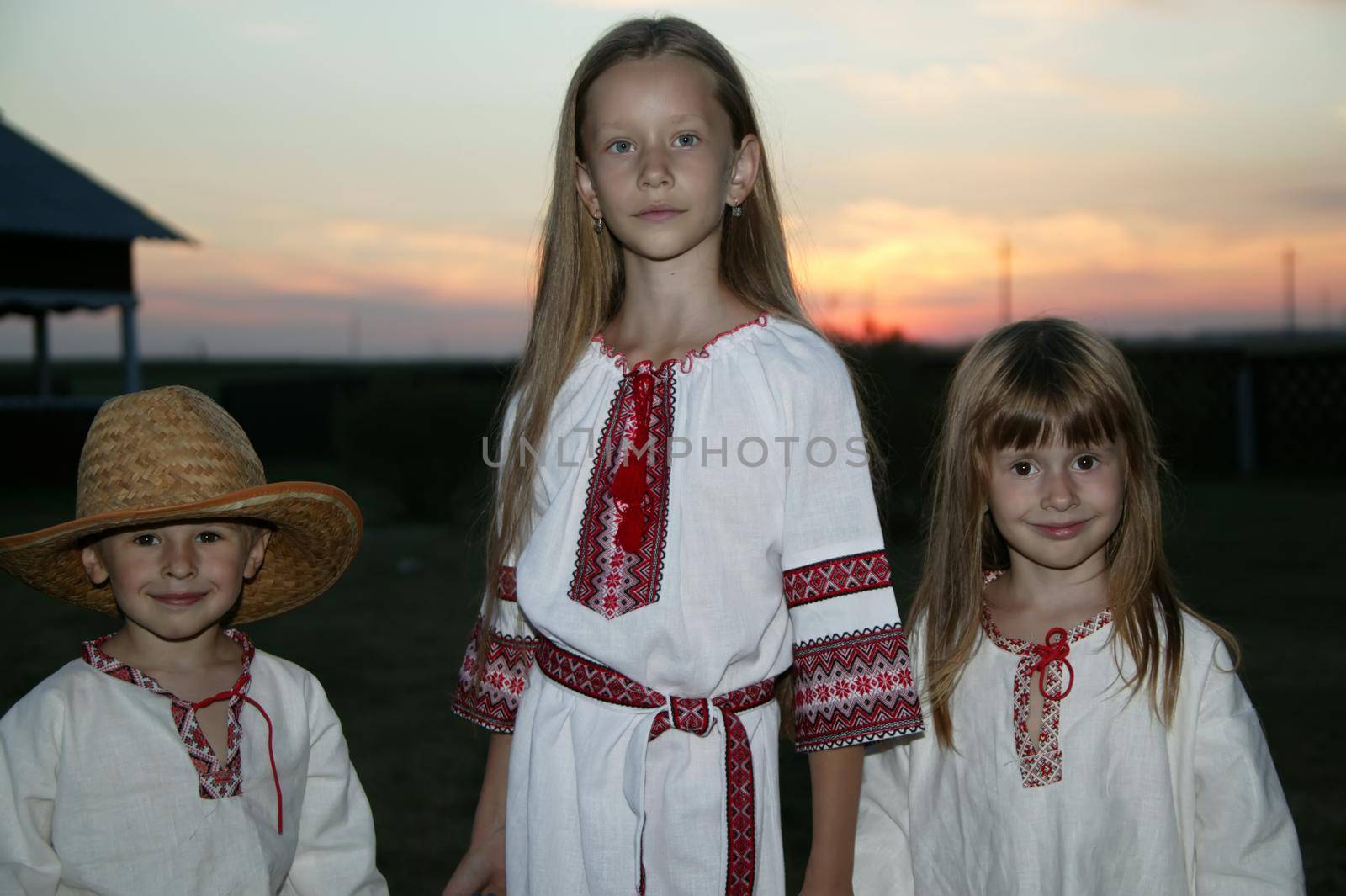 Slavic children in an embroidered shirt on a sunset background. Children are Ukrainian and Belarusians. People in national clothes. by Sviatlana