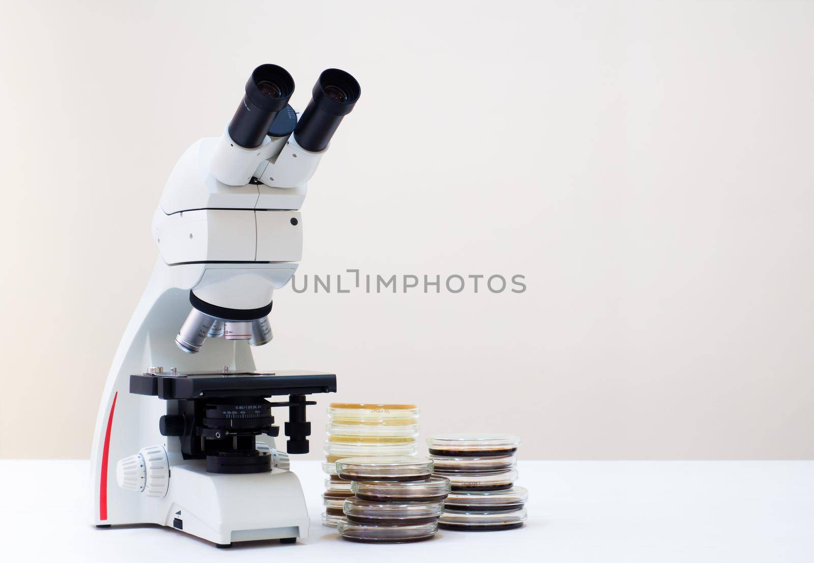 A microscope and petri dishes are near. by Jannetta