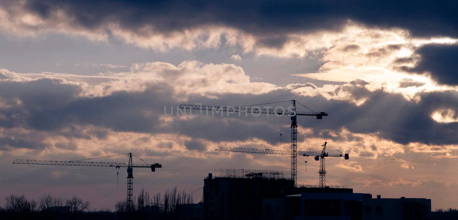 Silhouettes of building cranes at sunset. by Jannetta