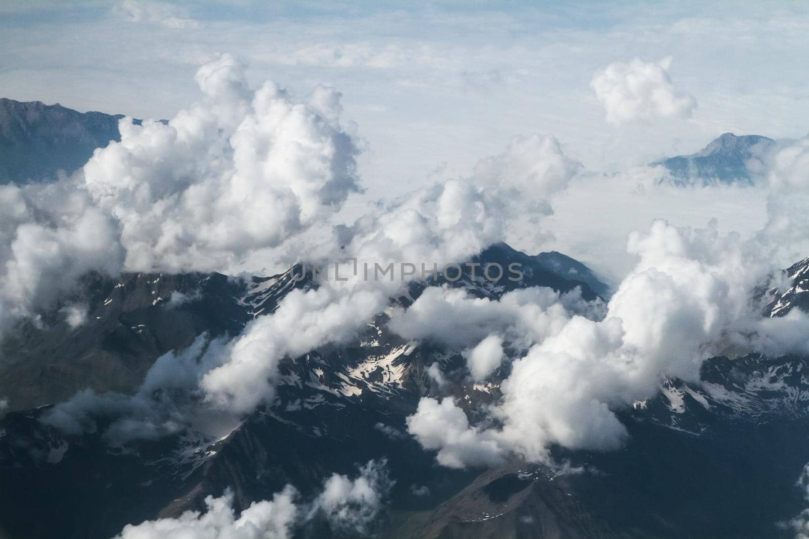 Mountain peaks in the clouds, top view, from the airplane. by Jannetta