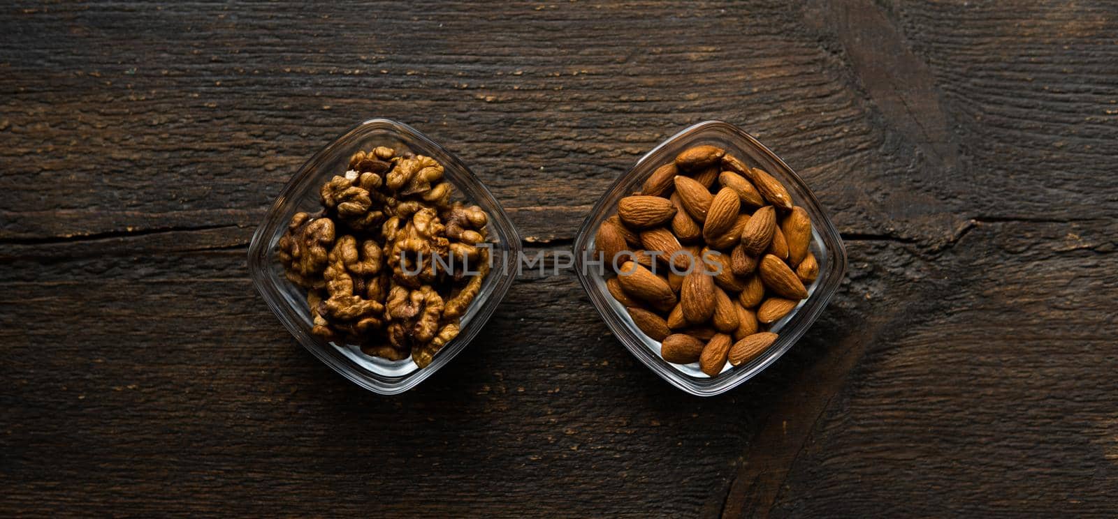 Almond and walnut in a small plates which standing on a vintage wooden table. Nuts is a healthy vegetarian protein and nutritious food