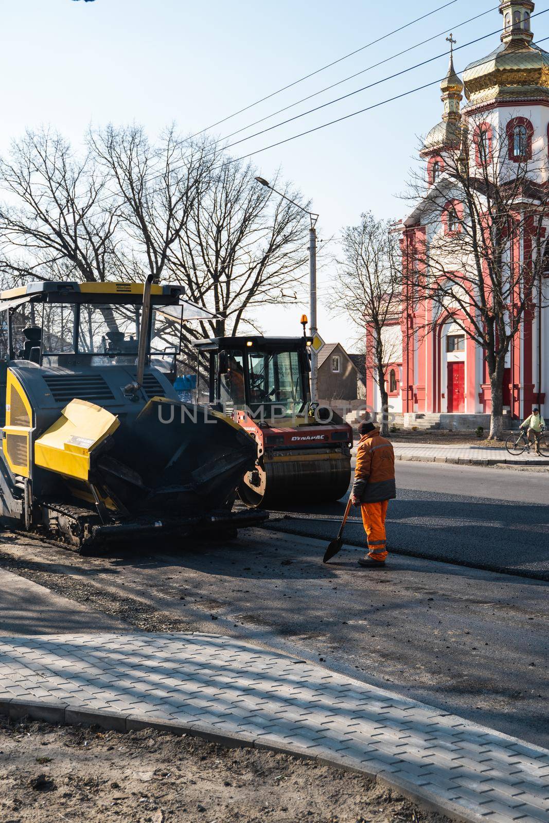 KYIV, UKRAINE - September 10, 2020: Heavy asphalt road roller with heavy vibration roller compactor that press new hot asphalt and asphalt paver machine on a road construction site on a street