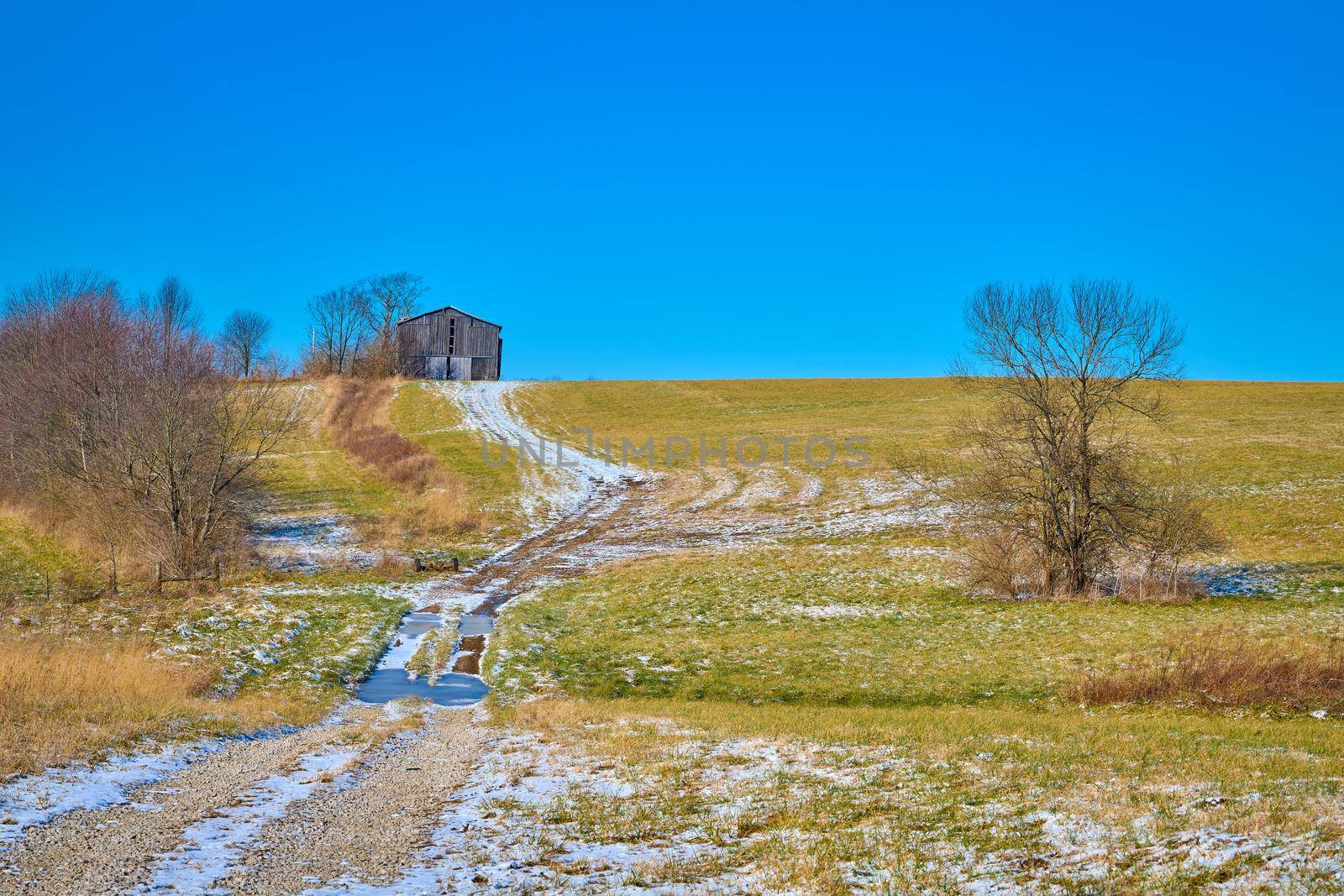 Tobacco barn sitting on a hill with snow covered path.