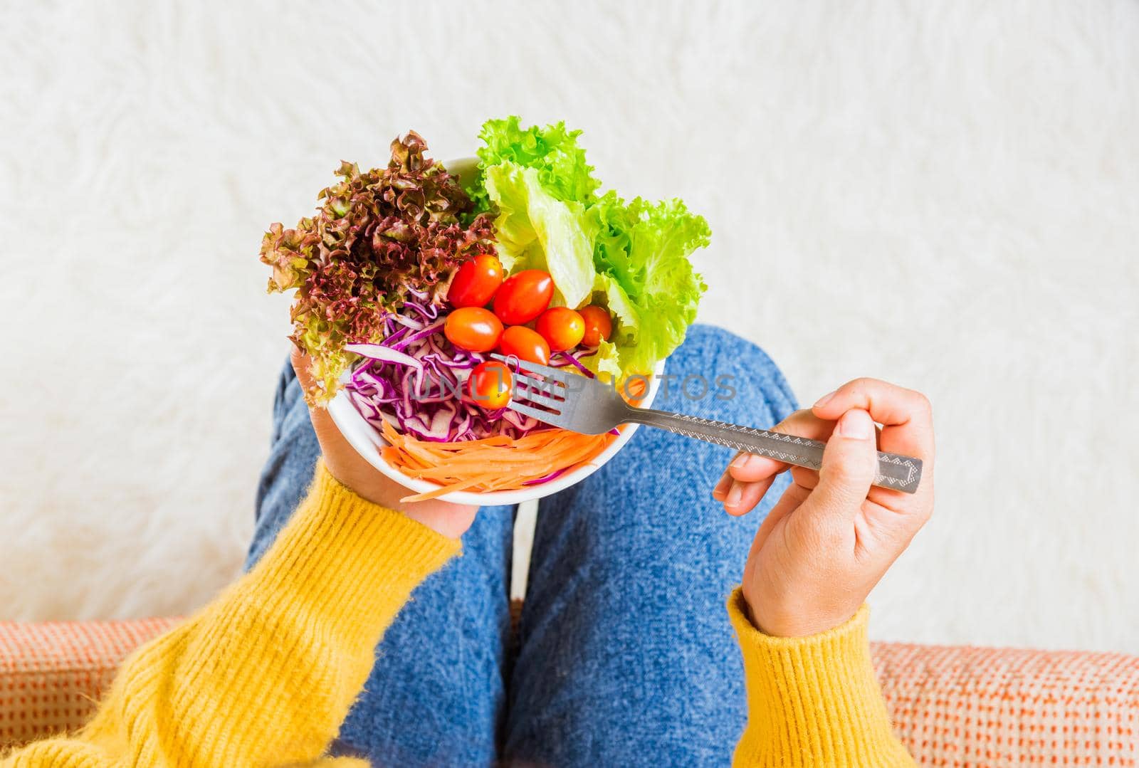 female hands holding bowl with green lettuce salad on legs by Sorapop